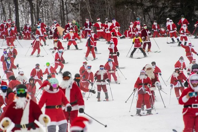 Three hundred plus skiers and snowboarders dressed as Santa Clause, and some other holiday characters, take off from the top of the mountain as they take part in the “Santa Sunday” event at Sunday River Resort in Newry, Maine on December 11, 2022. Money raised by the the event goes towards the River Fund Maine charity. (Photo by Joseph Prezioso/AFP Photo)