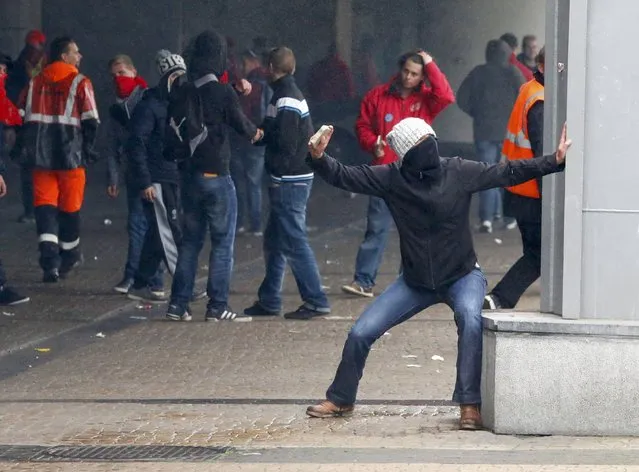 A demonstrator throws a projectile during clashes at a march against government reforms and cost-cutting measures in Brussels , October 7, 2015. (Photo by Yves Herman/Reuters)
