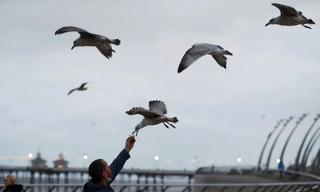A man feeds chips to gulls as they fly over the promenade in Blackpool, Britain, September 5, 2020. (Photo by Phil Noble/Reuters)