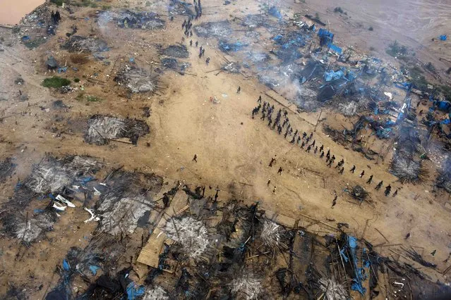 In this November 12, 2014 photo, a column of policemen occupy a gold mining camp as part of an operation to eradicate illegal mining in the area  known as La Pampa, in Peru's Madre de Dios region. Less than a month before Peru plays host to global climate talks, the government sent a battalion of police into southeastern jungles to dismantle illegal gold-mining mining camps. (Photo by Rodrigo Abd/AP Photo)