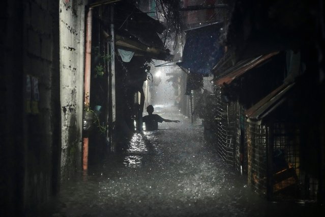 A man wades along waist-deep floods at a residential area after Tropical Storm Wipha caused intensified monsoon rains that bought flooding in Quezon city, Philippines, on Monday, July 21, 2025. (Photo by Aaron Favila/AP Photo)