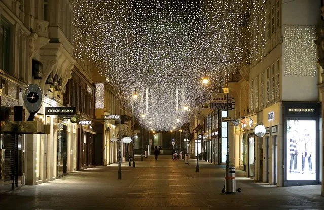In this Monday, November 23, 2020 file photo, the traditional Christmas lights shine over closed shops in downtown Vienna, Austria. Nations are struggling to reconcile cold medical advice with a holiday tradition that calls for big gatherings in often poorly ventilated rooms, where people chat, shout and sing together, providing an ideal conduit for a virus that has killed over 350,000 people in Europe so far. (Photo by Ronald Zak/AP Photo/File)