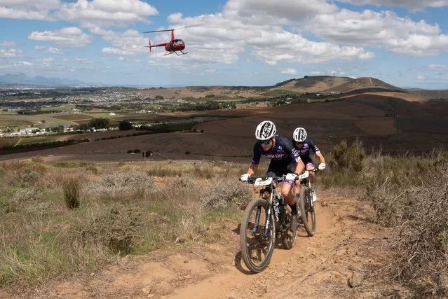 Georg Egger(L) and Lucas Baum cycle on the course during the prologue stage of the 2023 Cape Epic mountain bike stage race, in Durbanville, near Cape Town on March 19, 2023. The Cape Epic, in which two riders race as a team, is widely known as one of the foremost mountain bike stage race in the world, with the riders from all around the world covering a distance of approximately 700 kilometres, and gaining over 16000m in height, over eight days of racing. (Photo by Rodger Bosch/AFP Photo)