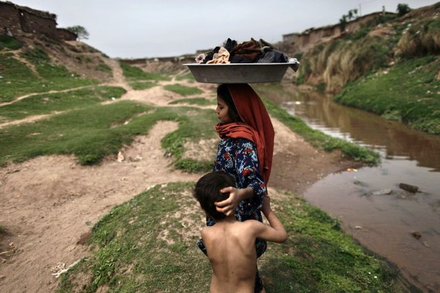 An Afghan refugee girl carries her laundry on her head after washing it in a polluted stream on World Water Day in a poor neighborhood on the outskirts of Islamabad, Pakistan, Friday, March 22, 2013. (Photo by Muhammed Muheisen/AP Photo)