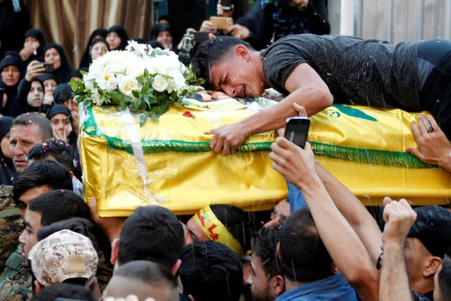 A man reacts while clenching onto the coffin of Hezbollah fighter Jalal al-Effie, who was killed during clashes in Syria's Aleppo, during his funeral in Beirut's southern suburbs, Lebanon October 18, 2016. (Photo by Aziz Taher/Reuters)