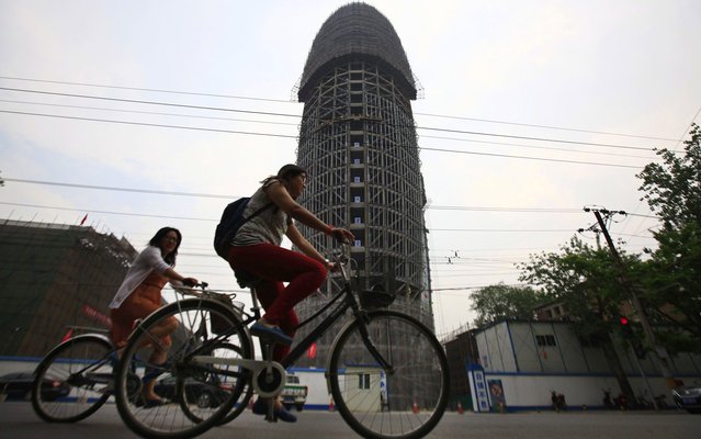People ride past the unfinished office building of People's Daily, the official newspaper of the communist party of China, in Beijing, May 8, 2013. Some Chinese bloggers ridiculed that the building's outline, which they claim resembled the male genital, matched perfectly with the China Central Television (CCTV) tower that has been nicknamed “Big Underpants”. (Photo by Petar Kujundzic/Reuters)