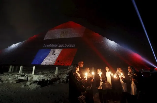 Egyptians light candles as the French and Egyptian flags and France's national colours of blue, white and red are projected onto one of the Giza pyramids, in tribute to the victims of the Paris attacks, on the outskirts of Cairo, Egypt, November 15, 2015. The words on the pyramid read: "Solidarity with France". (Photo by Amr Abdallah Dalsh/Reuters)