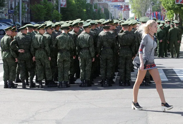 A woman walks past servicemen of the self-proclaimed Donetsk People's Republic (DNR), who take part in a rehearsal for the Victory Day parade in Donetsk, Ukraine on May 3, 2018. (Photo by Alexander Ermochenko/Reuters)