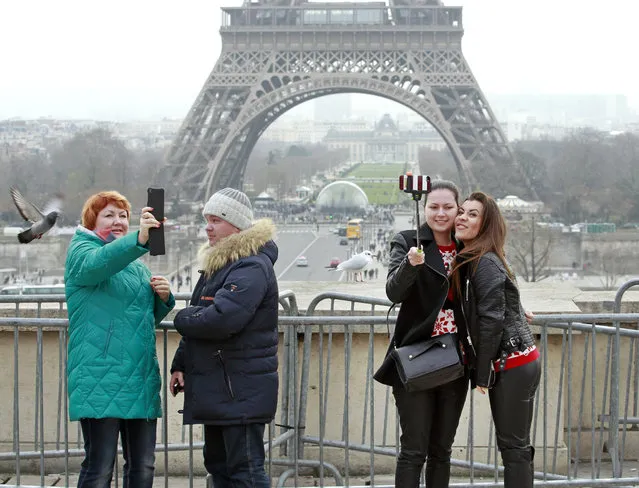 Tourists use a selfie stick on the Trocadero Square, with  the Eiffel Tower in background, in Paris, Tuesday, January 6, 2015. (Photo by Remy de la Mauviniere/AP Photo)