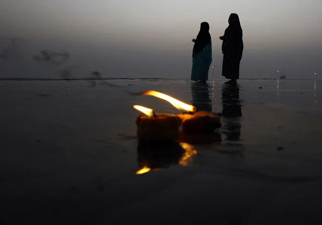 Hindu pilgrims pray behind burning oil lamps after they took a holy dip at the confluence of the river Ganges and the Bay of Bengal, ahead of the “Makar Sankranti” festival at Sagar Island, south of Kolkata, January 12, 2015. (Photo by Rupak De Chowdhuri/Reuters)