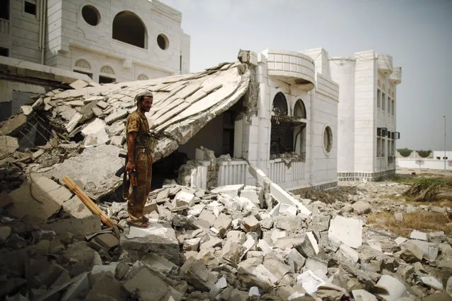 An army soldier stands guard at a local authority compound damaged during recent fighting between the army and al Qaeda-linked militants in southern Yemeni city of Zinjibar June 14, 2012. (Photo by Khaled Abdullah/Reuters)