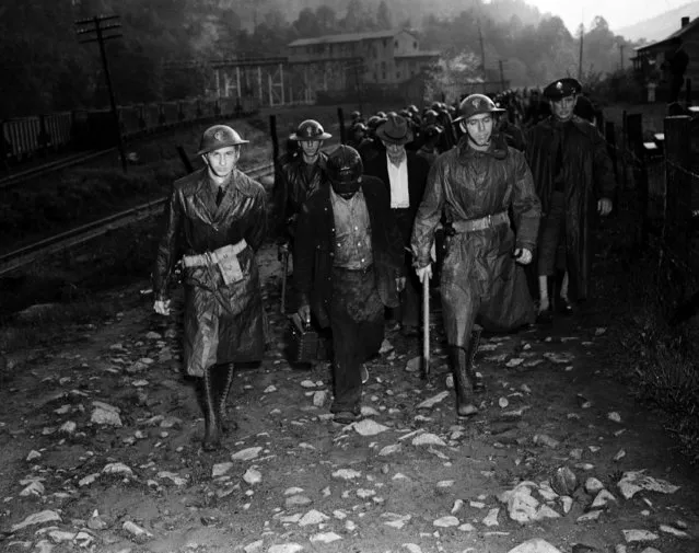 Their day's work done, miners who reported for duty at the Harlan Central Coal Company workings near Harlan, Ky., are shown leaving the mine under the guard of troops who escorted them through the picket line on May 16, 1939. (Photo by Preston Stroup/AP Photo)