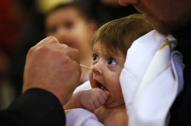 A baby is baptised during a mass baptism ceremony on Epiphany day in Tbilisi, January 19, 2015. About 1000 children were baptised by the Georgian Orthodox church during the 38th mass baptism ceremony at the country's main cathedral Holy Trinity. (Photo by David Mdzinarishvili/Reuters)