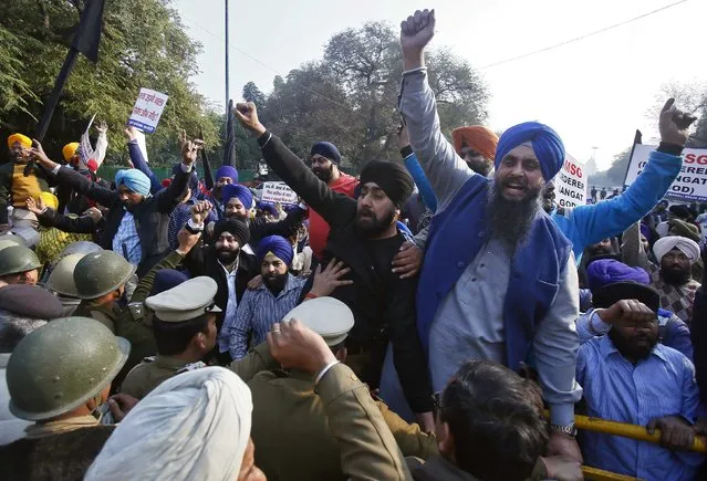 Indian policemen (L) try to stop demonstrators from the Sikh community from crossing over the barricades during a protest against the impending release of an Indian film “MSG: The Messenger of God”, in New Delhi January 16, 2015. Several groups representing the Sikh minority. (Photo by Anindito Mukherjee/Reuters)