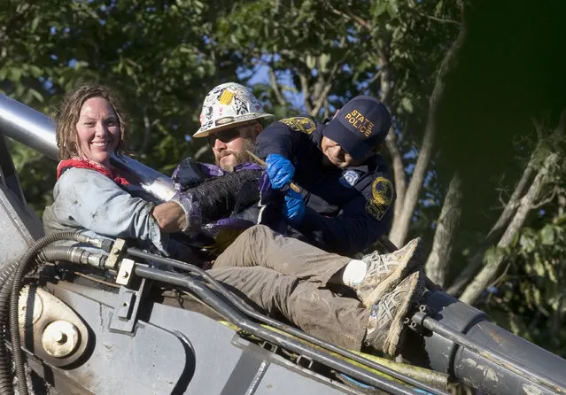 State police work to remove Virginia Tech professor Emily Satterwhite from construction equipment along the Mountain Valley Pipeline route on Brush Mountain in Montgomery County, Va., Thursday, June 28, 2018. The Roanoke Times reports Satterwhite took up her position on an excavator early Thursday on Brush Mountain. Satterwhite teaches Appalachian studies and has been active in pipeline protests. (Photo by Heather Rousseau/The Roanoke Times via AP Photo)