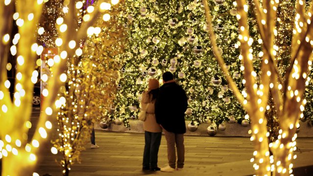 A couple stand at the base of an ornate 75-foot Christmas tree at CityCenterDC in Washington, U.S., December 19, 2024. (Photo by Kevin Lamarque/Reuters)