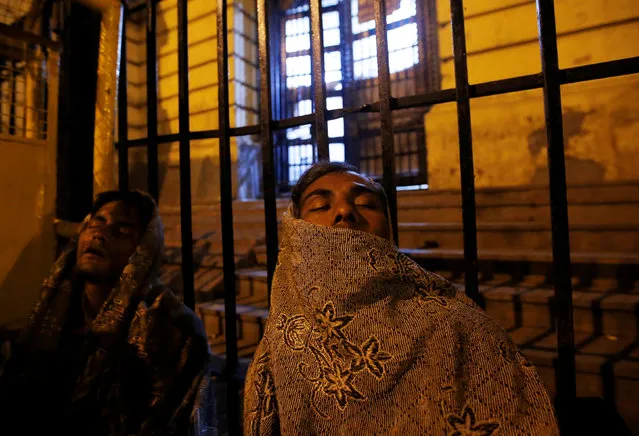 Men sleep outside a bank as they wait for the bank to open to exchange their old high denomination bank notes in the early hours, in the old quarters of Delhi, India, November 16, 2016. (Photo by Adnan Abidi/Reuters)