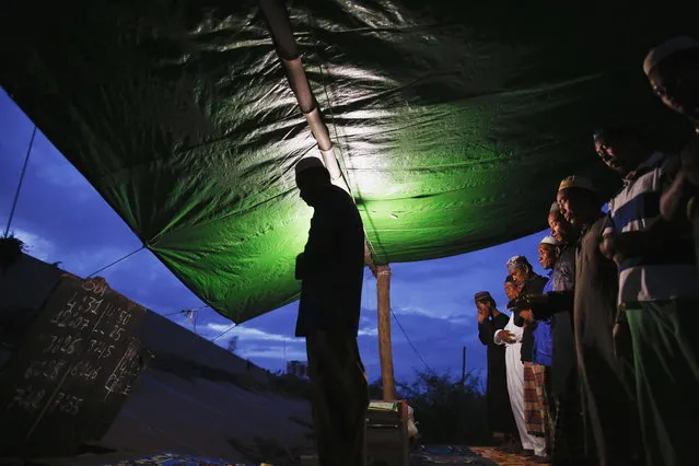 The exact times for the five daily prayers are written on a small board (L) as ethnic Cham Muslims pray at their makeshift mosque on the banks of the Mekong river in Phnom Penh July 29, 2013. About 100 ethnic Cham families, made up of nomads and fishermen without houses or land who arrived at the Cambodian capital in search of better lives, live on their small boats on a peninsula where the Mekong and Tonle Sap rivers meet, just opposite the city's centre. The community has been forced to move several times from their locations in Phnom Penh as the land becomes more valuable. They fear that their current home, just behind a new luxurious hotel under construction at the Chroy Changva district is only temporary and that they would have to move again soon. (Photo by Damir Sagolj/Reuters)