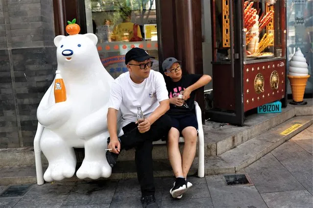 People rest outside a store amid the orange alert for heatwave, in Beijing, China on July 5, 2023. (Photo by Tingshu Wang/Reuters)