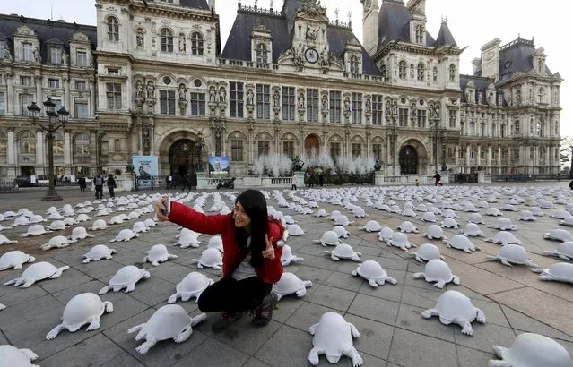 A Malaysian tourist takes a selfie near French artist Rachid Khimoune's installation which features a thousand turtle-shaped sculptures in front of the city hall in Paris, France December 19, 2015. (Photo by Jacky Naegelen/Reuters)
