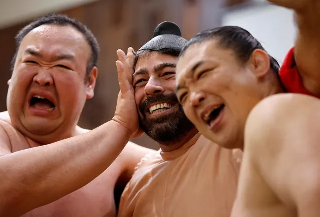 Former sumo wrestlers Kotoohtori, 40, and Towanoyama, 45, pose for a photograph with a tourist from the U.S., who is wearing a sumo wrestler costume, on the sumo ring at Yokozuna Tonkatsu Dosukoi Tanaka in Tokyo, Japan on June 30, 2023. (Photo by Issei Kato/Reuters)
