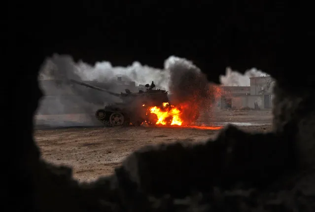 A tank is seen afire during clashes between soldiers from the Libyan National Army, led by Marshal Khalifa Haftar, and jihadist fighters on November 30, 2016 in the area of Qanfudah, south of Benghazi Benghazi, birthplace of Libya' s 2011 revolution which toppled longtime dictator Moamer Kadhafi, has been the scene of daily clashes for the past two years between armed forces of Haftar and jihadists holding onto pockets of the city. (Photo by Abdullah Doma/AFP Photo)
