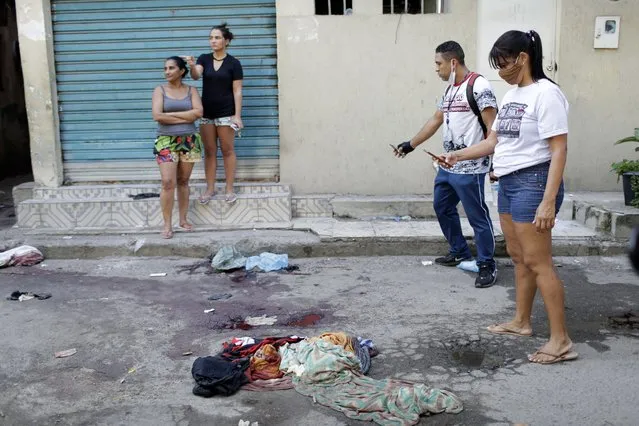 Residents take pictures of blood on the street after a police operation targeting drug traffickers in the Jacarezinho favela of Rio de Janeiro, Brazil, Thursday, May 6, 2021. (Photo by Silvia Izquierdo/AP Photo)