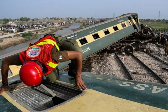 A rescue worker searches for victims after a train derailed in Sarhari town in district Sanghar, Pakistan on August 6, 2023. (Photo by Yasir Rajput/Reuters)