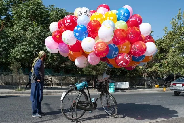 An Afghan balloon vendor stands aside his bicycle as he awaits customers at a street in Kabul on August 31, 2023. (Photo by Wakil Kohsar/AFP Photo)