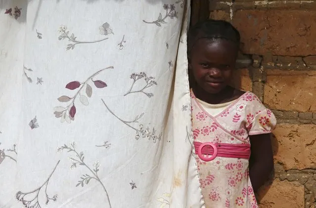 A child looks out from behind a curtain during a visit by a home-based care team to an HIV-positive person in the village of Choongo, south of the Chikuni Mission in the south of Zambia February 23, 2015. (Photo by Darrin Zammit Lupi/Reuters)