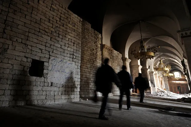 People walk past a shrine protected by cement blocks inside the Umayyad mosque, in the government controlled area of Aleppo, Syria December 17, 2016. (Photo by Omar Sanadiki/Reuters)