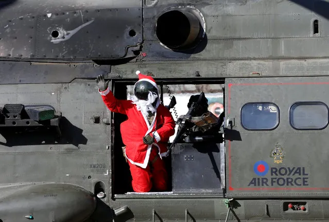 A soldier from Resolute Support (RS) troops dressed as Santa Claus, waves from a military helicopter during a football match to commemorate the Christmas Truce of 1914 at the ISAF Headquarters, in Kabul, Afghanistan December 25, 2016. (Photo by Omar Sobhani/Reuters)