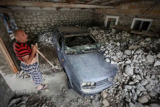 A man stands next to a car damaged by flooding after heavy rainfall in Yalta, Crimea on June 22, 2021. (Photo by Alexey Pavlishak/Reuters)