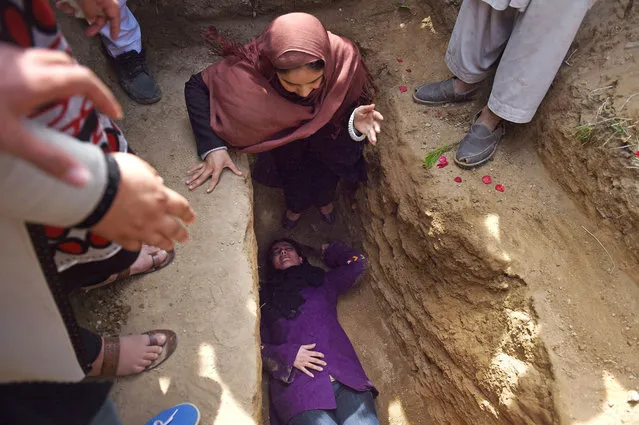 Independent Afghan civil society activist women weep and lie on the grave of Afghan woman Farkhunda, 27, who was lynched by an angry mob, at the cemetary in central Kabul on March 22, 2015.  Hundreds of people on March 22, attended the burial of an Afghan woman who was beaten to death and set on fire by a mob for allegedly burning a copy of the Koran.  (Photo by Wakil Kohsar/AFP Photo)