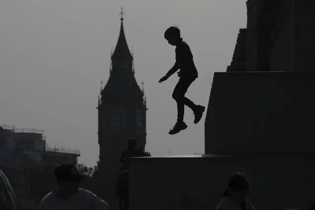 A boy jumps down from a statue at Trafalgar Square with the background of the Elizabeth Tower, known as Big Ben, in London, Monday, October 9, 2023. (Photo by Kin Cheung/AP Photo)