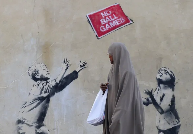 A pedestrian passes graffiti art on a wall in north London, September 24, 2009. British media have attributed the work to Banksy. (Photo by Toby Melville/Reuters)