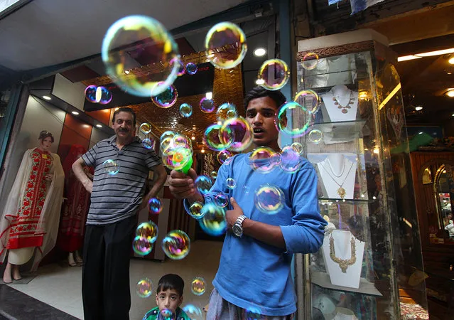 A street vendor blows soap bubbles to attract Eid customers at a local market in Srinagar, India on July 6, 2016. (Photo by Faisal Khan/Pacific Press/Barcroft Images)