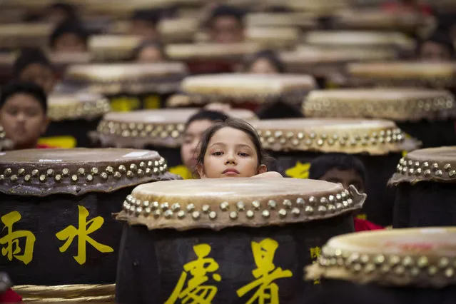 Young drummers stick out their heads among drums while preparing for the performance of “A Flourish of Hundreds Drums” in Kuala Lumpur, Malaysia, Sunday, January 8, 2017. In the event, a total of 388 drummers performed the 24 Festive Drums, a popular performance in Malaysia in which groups of drummers beat 24 drums that represent 24 solar terms in the lunar calendar. The drumming, part of the Malaysian Chinese culture, has its origins in the drums performed in harvest festivals in China. Chinese letters on drums read: “Limit of heat”, right, marked on about August 29, and “Rainwater”, left, marked on about February 19. (Photo by Lim Huey Teng/AP Photo)
