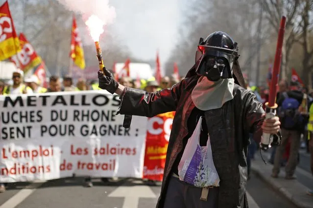 A worker, wearing a Darth Vader Mask, holds a flare as he attends a demonstration against austerity plans which affect salaries and pensions in Paris, April 9, 2015. French unions sought on Thursday to ramp up protests against public spending cuts, calling for work stoppages and marches by public-sector staff that coincided with strikes by air traffic controllers and state radio workers. (Photo by Benoit Tessier/Reuters)