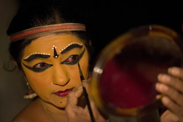 Indian classical dancer Usha Nangiar applies makeup as she prepares to perform her role as Draupadi during a three-day Kurathiyattam festival in Gauhati, India, Thursday, April 2, 2015. The festival was organized by the Sangeet Natak Akademi, Delhi. (Photo by Anupam Nath/AP Photo)