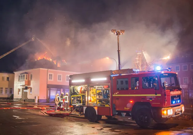 A fire engine stands in front of a burning building in Bautzen, eastern Germany, Sunday, February 21, 2016. The fire damaged a former hotel that was being converted into a refugee home and two people were detained after hindering firefighters' work, police said Sunday, days after an incident in which a mob blocked a bus carrying asylum-seekers in the same state. (Photo by Rico Loeb/DPA via AP Photo)