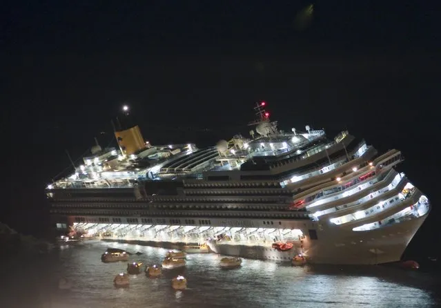 The luxury cruise ship Costa Concordia lays on its starboard side after it ran aground off the coast of the Isola del Giglio island, Italy on January 13, 2012. Italy is marking the 10th anniversary of the Concordia disaster with a daylong commemoration, honoring the 32 people who died but also the extraordinary response by the residents of Giglio who took in the 4,200 passengers and crew from the ship on that rainy Friday night and then lived with the Concordia carcass for another two years before it was hauled away for scrap. (Photo by Giuseppe Modesti/AP Photo)