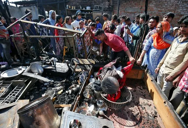 A man salvages his belongings after a fire broke out in a slum in Ahmedabad, February 21, 2019. (Photo by Amit Dave/Reuters)