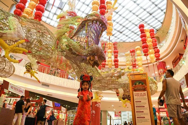 A girl in traditional Chinese costume poses for photos in front of a 500-foot-long dragon installation displayed at a mall in the Chinatown district of Manila on February 5, 2024, ahead of the Lunar New Year of the Dragon which falls on February 10. (Photo by Ted Aljibe/AFP Photo)