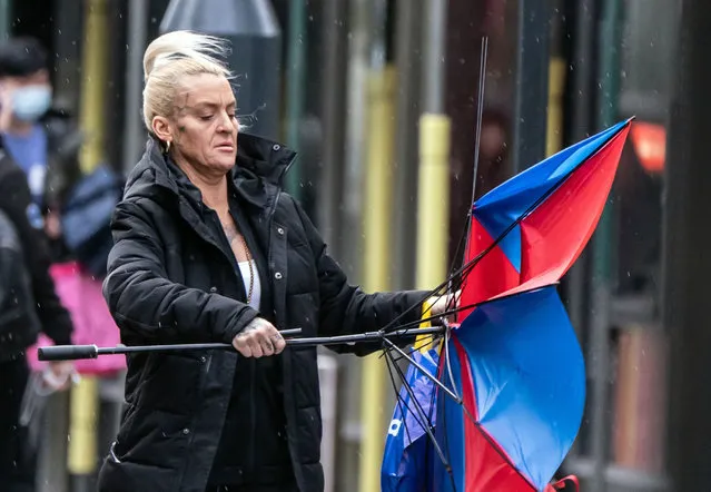 A woman with a broken umbrella in windy conditions in Leeds on Sunday, January 21, 2024. The UK is blanketed by “unusual” danger-to-life wind warnings ahead of Storm Isha, with people warned not to travel amid possible 90mph gusts. (Photo by Danny Lawson/PA Images via Getty Images)