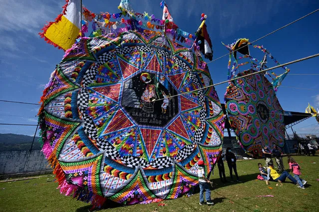 People prepare to fly a giant kite during the All Saints' Day commemoration, on the eve of the Day of the Dead, in Santiago Sacatepequez, some 50 km west of Guatemala City, on November 1, 2021. (Photo by Johan Ordonez/AFP Photo)