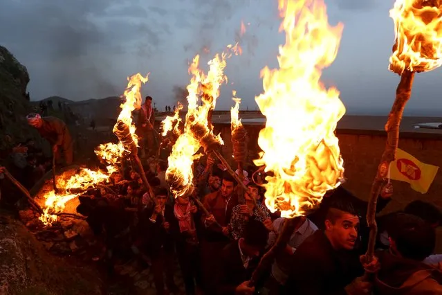 Iraqi Kurdish people carry fire torches up a mountain where a giant flag of Iraq's autonomous Kurdistan region is laid, as they celebrate Newroz Day, a festival marking their spring and new year, in the town of Akra, Iraq March 20, 2016. (Photo by Ari Jalal/Reuters)