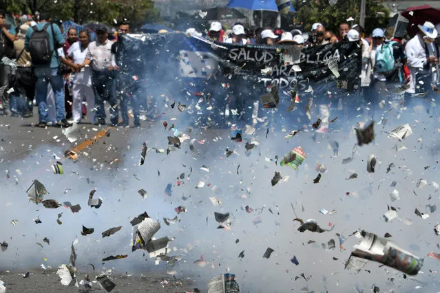High-school teachers, medical doctors and university students celebrate with firecrackers as they march towards the Congress building against education and healthcare reforms in Tegucigalpa on April 30, 2019, after a law approved last week was repealed. Some 4,000 people including teachers, students and employees of public hospitals resumed protests Tuesday in Tegucigalpa, in spite of the promise of the Congress' president of giving up the reforms that triggered demonstrations. (Photo by Orlando Sierra/AFP Photo)