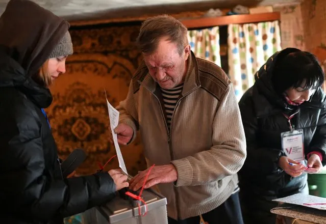 A man casts his vote in a mobile ballot box as members of a local electoral commission visit his home during the presidential election in the village of Novoaleksandrovka in the Omsk Region, Russia, on March 15, 2024. (Photo by Alexey Malgavko/Reuters)