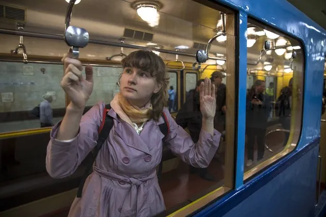 People come to have a look at a Soviet-era vintage subway car, parked in the Partizanskaya subway station in Moscow, Russia, Friday, May 15, 2015. Vintage Soviet-era metro cars were exhibited at the Partizanskaya subway station as part of festivities marking the 80th anniversary of the Moscow subway on Friday. (Photo by Pavel Golovkin/AP Photo)